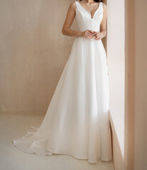Front view of beautiful bride dressed in a white long wedding dress with deep neckline. Classic wedding sleeveless dress