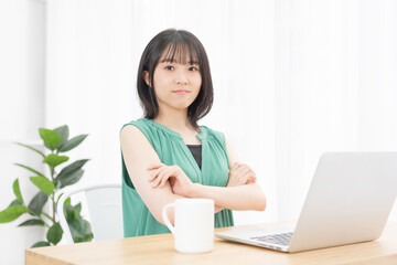 Fototapeta premium PCを使いながら腕組みしている若い女性
