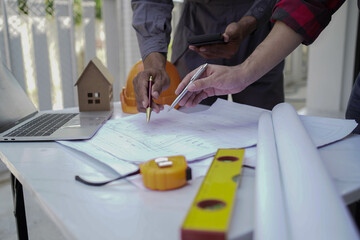 Smiling young architect or engineering builder in hard hat with tablet over group of builders at construction site, architect watching some a construction, business, building, industry, people concept