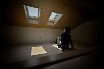 Obraz premium A woman looking through a window in the roof in a dark attic