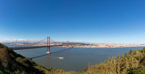 Panoramic landscape of the April 25 bridge over the Tagus river and the Lisbon city in the background