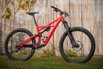 Fototapeta na wymiar Side view of a modern mountain bike or bicycle for off road. Enuduro mtb bicycle parked on a lawn. Red MTB standing upright on grass, static, no people.