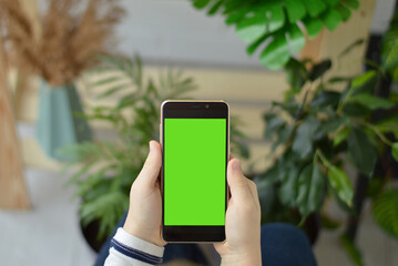 Close-up of children's hands holding a smartphone with a green screen.