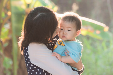 Fototapeta premium Soft focus portrait of happy loving mother and her baby outdoors,Beautiful young mother holds a baby
