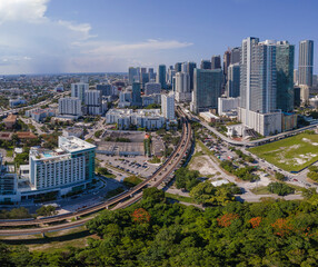 Fototapeta premium Aerial view of Miami Florida with buildings roads and trees on a sunny day. Beautiful urban landscape with condominiums and skyscrapers on the city skyline against blue sky.