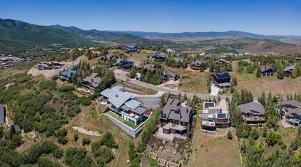 Fototapeta na wymiar Aerial view of beautiful mountain houses on a sunny day in Park City Utah. Residential neighborhood landscape surrounded by trees and scenic nature views.