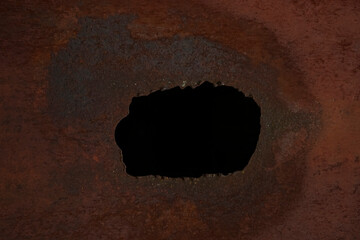 dark black hole in brown rusty metal wall. breaking the wall . iron background.