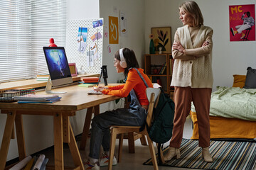 Mom forbidding to play computer games to her child, while she sitting at table and playing on...
