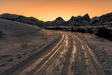 Track on the snow towards the Casares Reservoir and Peñas de Cubillas de Arbas in the background at sunset, León, Spain.