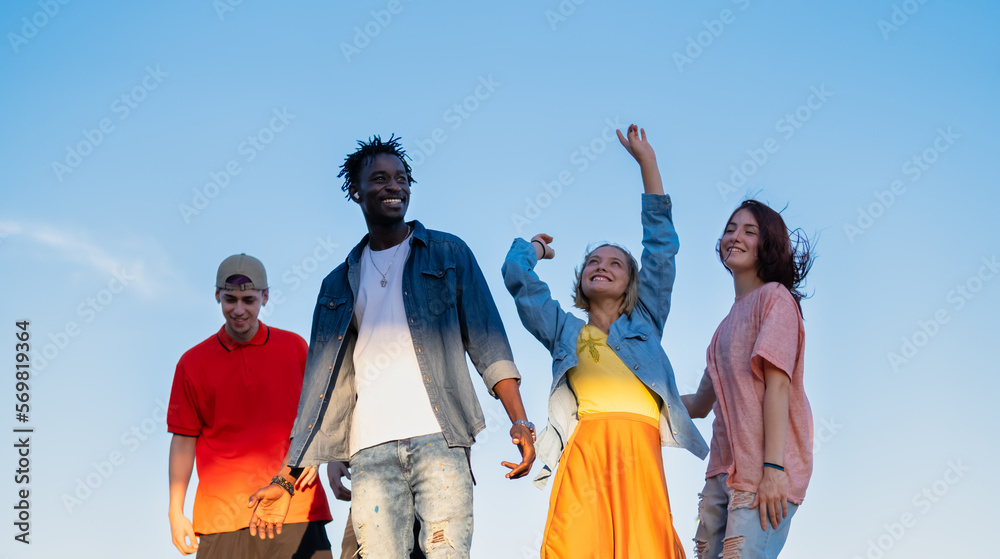 Wall mural Group of multiracial friends having fun in the park outside dancing together - together again