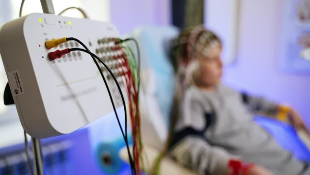 Sensor board for brain examination. Close up. Boy undergoing check up at backdrop in blur.