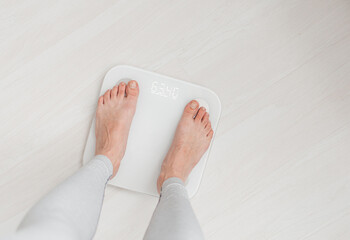 Woman leg stepping on scales at home. Measurement instrument in kilogram for diet Lose weight...