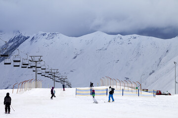 Fototapeta na wymiar Ski slope with skiers and snowboarders in evening