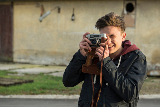 Young man clicking pictures with retro styled camera, Munich, Bavaria, Germany