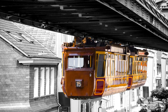 Historic Suspension Railway in Wuppertal Germany. Oldtimer &ldquo;Schwebebahn&ldquo; hanging under a steel construction above the narrow streets of Vohwinkel. Unique and very safe transportation vehicle.