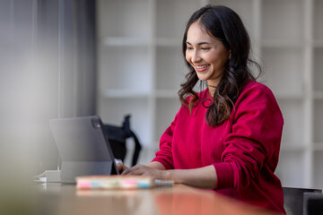 Happy Young Indian Asian Business woman sitting on Digital Tablet work desk Workplace. 