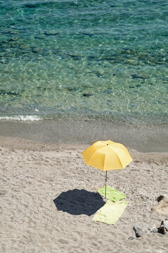 Yellow beach umbrella water sand towel deserted
