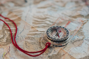 Close up detail of a compass on top of a topographic map. Planning an outdoor adventure.