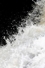 Close focus on splashing water of waterfall with dark background.