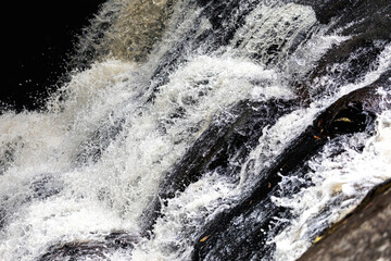 Obraz premium Splashing water on rocky slope of waterfall inside tropical rainforest.