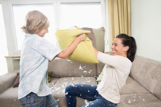 Woman pillow fighting with her son in living room, Bavaria, Germany