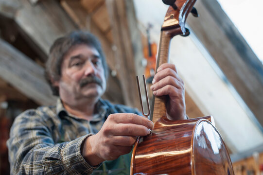 Craftsman in workshop holding violin