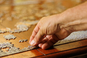 Fototapeta na wymiar mans hand placing jigsaw puzzle piece