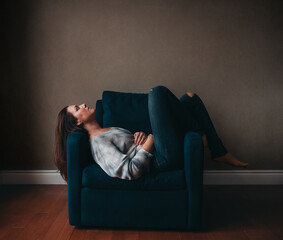 Attractive woman resting in a comfortable chair in an empty room.