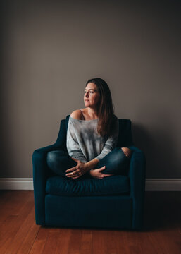 Attractive woman sitting in a comfortable chair in an empty room.