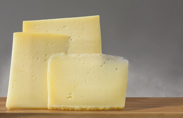 Three pieces of hard cheese on a gray background