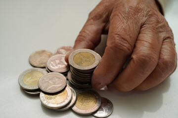 Retired elderly woman counting coins money and worry about monthly expenses and treatment fee payment.
