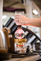 Professional coffee maker - Barista using coffee siphon brewing hot espresso at coffee shop coffee brewing syphon alternative method. Startup Business Concept.