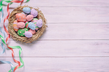 Easter background, a nest with painted eggs and colorful ribbons on a light wood. Space for tex. High quality photo
