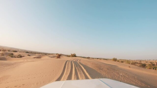 4K POV of a vehicle dune bashing on the sand dunes of the Thar desert at Jaisalmer in Rajasthan, India. Car moves on the desert during the day. Extreme adventure in the desert background.
