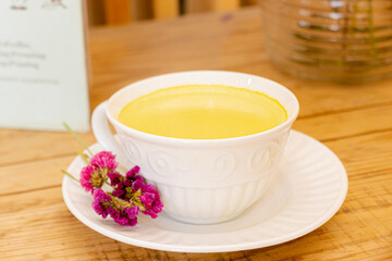 Smoothe/frapuccino amarillo de maracuyá en taza blanca y flores secas a un lado
