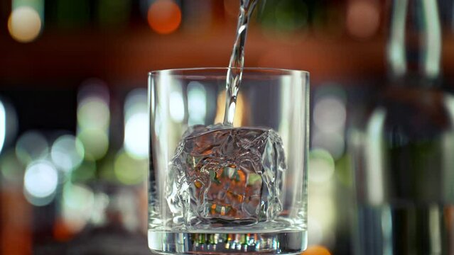 Super Slow Motion Shot of Pouring Vodka into Glass With Perfect Ice Cube on Bar at 1000fps.