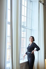 A beautiful woman is standing at a large window