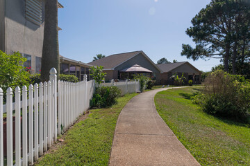 Concrete walkway along the houses with white picket fence in Navarre, Florida. Row of fenced houses...