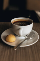 White cup of hot coffee americano with cookies on the table