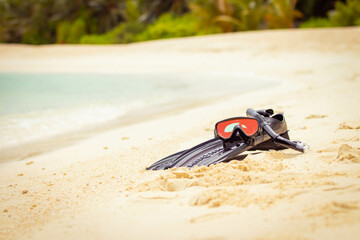 Swimming flippers and snorkeling mask laying on the beach in the sand
