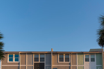 Adjacent box homes creating a straight line from clear sky above in Destin, Florida. Building complex exterior with trims on its painted stucco wall.