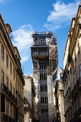 Obraz premium Scenic cityscape view of ancient part of the Lisbon city. Old Santa Justa Lift between vintage colorful buildings. Architectural icon of the city of Lisbon. Travel and tourism concept