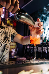 man hand bartender making sweet and sour refreshing Aperol Spritz cocktail on the bar counter