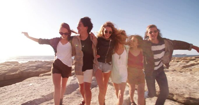 Group of multi-ethnical friends in hipster style embracing each other joyfully on a sunny day