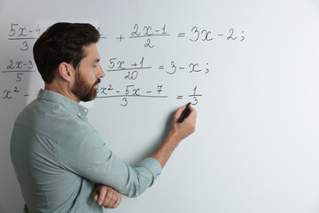 Mature teacher explaining mathematics at whiteboard in classroom