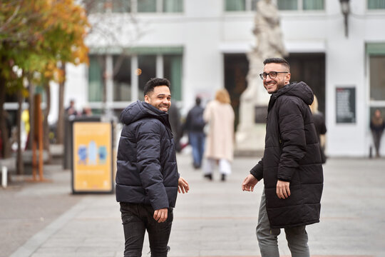 Two Men Looking At Camera And Smiling While Walking Outdoors On The Street.