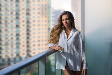 Fototapeta premium Morning healthy breakfast. Young woman with glass of milk on balcony terrace. Girl drinking milk at home. Beautiful woman holding milk glass. Lactose free milk, concept. Morning beverage.