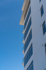 Apartment's side in a low angle view against the clear sky at Destin, Florida. Apartment exterior with tinted picture windows and balconies at the corner.