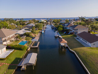 Fototapeta na wymiar Intracoastal residential area at Navarre, Florida with private boat docks. Houses with lawn yard near the waterway in the middle heading to the bayfront against the clear sky in an aerial shot view.