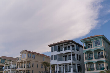 Beach houses with modern facade under the giant clouds in the sky in Destin, Florida. Front exterior of beach houses with balconies in a row.